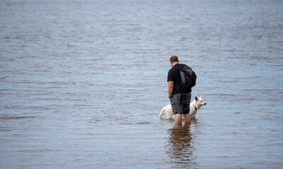 man in the water with his Swiss shepherd dog
