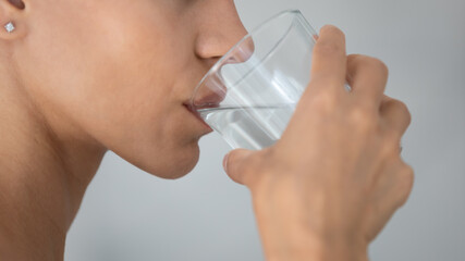 Close up side view of young woman drink clean mineral water from glass in home bath, millennial...