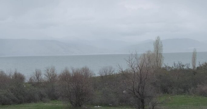 Capture the panoramic view of mist-shrouded Lake Sevan in Armenia, where the ethereal mist adds an enchanting quality to the serene landscape.