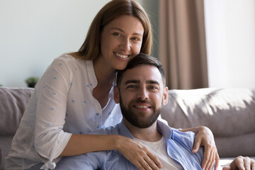 Obraz premium Happy beautiful young woman and handsome man in love home head shot portrait. Attractive couple enjoying love romantic relationship, leisure time at home, hugging, looking at camera with toothy smiles