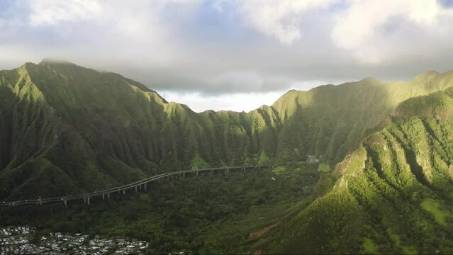 Scenic aerial with transportation background, travel summer trip 4K. Epic view on H-3 interstate running by cinematic Hawaii island Oahu. Famous mountain road with jungle nature landscape at sunrise