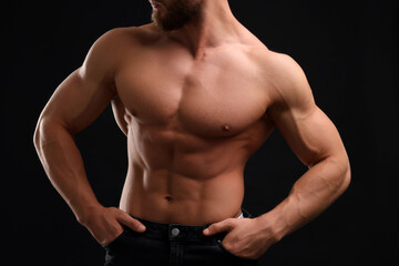 Fototapeta na wymiar Muscular man showing abs on black background, closeup. Sexy body