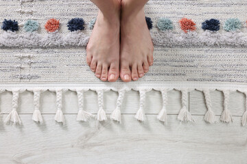 Woman standing on carpet with pattern at home, top view