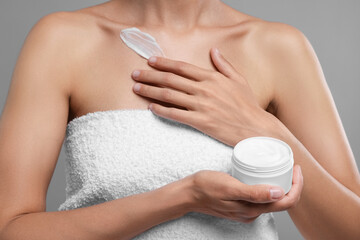 Obraz na płótnie Canvas Woman applying cream onto body on grey background, closeup