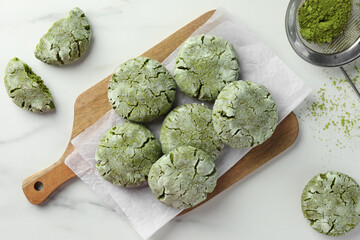 Board with tasty matcha cookies and powder on white marble table, flat lay