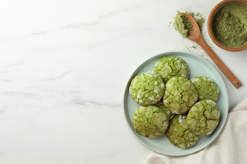 Plate with tasty matcha cookies and powder on white marble table, flat lay. Space for text