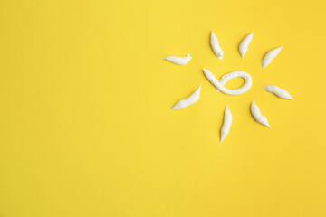 Drawing of sun with cream on yellow background, top view and space for text. Skin care and protection