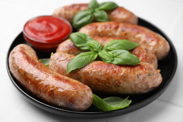 Plate with tasty homemade sausages, ketchup and basil leaves on white table, closeup