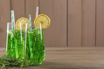 Glasses of refreshing tarragon drink with lemon slices on wooden table, space for text - obrazy, fototapety, plakaty