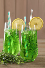 Glasses of refreshing tarragon drink with lemon slices on wooden table