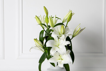 Beautiful bouquet of lily flowers near white wall