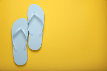 Stylish white flip flops on yellow background, top view. Space for text