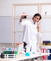 Young handsome chemist working in the lab