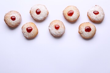 Hanukkah donuts with jelly and powdered sugar on white background, flat lay. Space for text