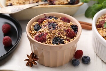 Tasty baked oatmeal with berries and anise star on white table, closeup