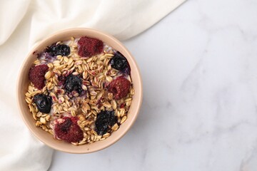 Tasty baked oatmeal with berries on white marble table, top view. Space for text