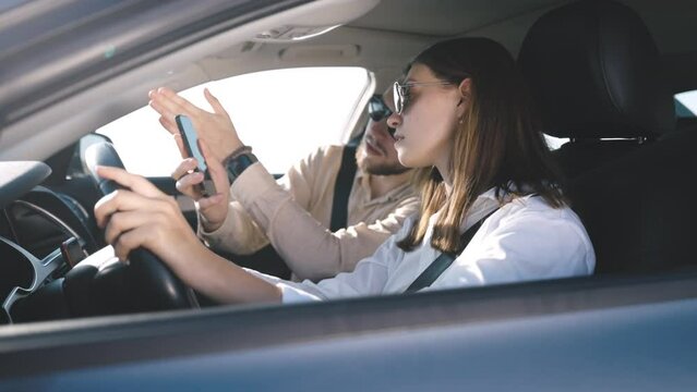 Woman driving car, while young man in front seat used smartphone to display map on screen, concept of navigation