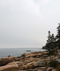 A couple sits in the rocks staring at the Atlantic Ocean 