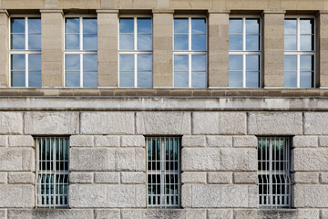 Naklejka premium Front exterior view of modern facade with cream brown rough granite stone tile wall and high windows on symmetric rectangular pattern.