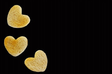 Roasted cut out heart shaped slice of toast bread in black background,selective focus with copy space