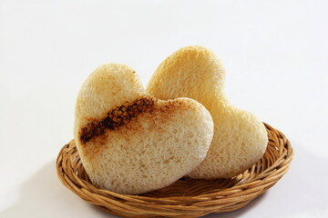 Roasted cut out heart shaped slice of toast bread in basket on white background - Powered by Adobe