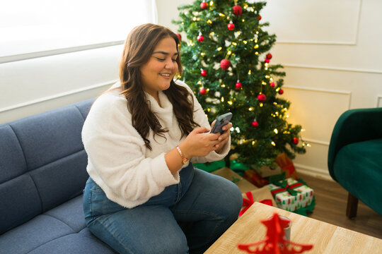 Happy woman with a smartphone texting about christmas gifts
