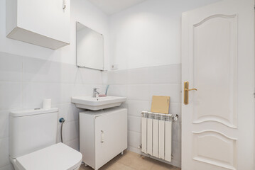 Fototapeta na wymiar Bathroom with small white porcelain sink under a suspended mirror, white aluminum radiator and white square furniture