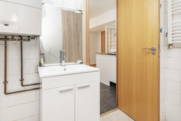 Toilet with small white porcelain sink under an unhung mirror