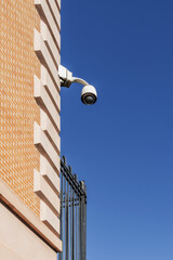 Surveillance cameras hanging from the stone blocks of a building with clay brick walls overlooking...
