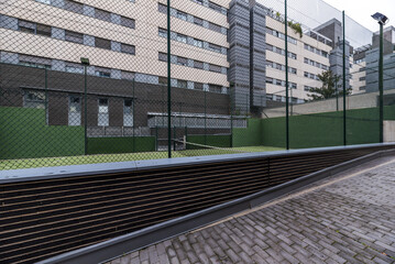 Paddle tennis court closed with metal fences and painted completely green in the common areas of a...