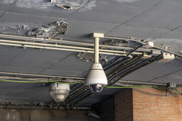 Surveillance camera hanging from the ceiling in an area with peeling paint