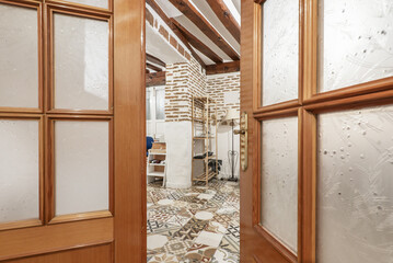 Cherry-colored wooden doors with translucent glass give access to a room with hydraulic stoneware...