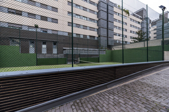 Paddle tennis court closed with metal fences and painted completely green in the common areas of a residential housing complex