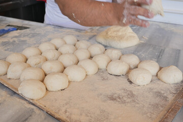 Female hands form pieces of dough for baking bread and rolls. 
