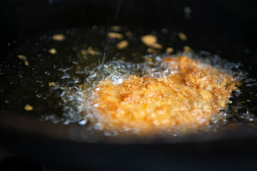 Fried chicken in a sieve on the stove. Selective focus.