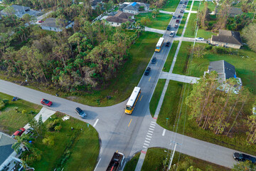 Aerial view of american yellow school bus picking up children at sidewalk bus stop for their...