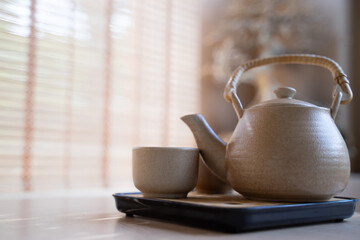 Teapot and tea cups, tea set on a tray placed on the table, blurred background, morning light