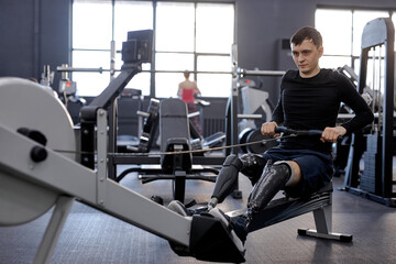 strong man concentrated on pilling rowing machine, side view shot. total-body fitness