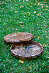 Two Shaman's tambourine made of genuine leather lie on the green grass.