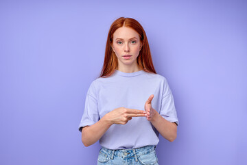 British sign language. A two-handed alphabet. Fingerspelling alphabet. red-haired woman showing deaf mute BSL alphabet letter V. closeup portrait isolated blue background