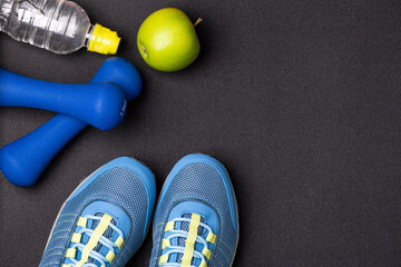 Sport shoes and equipment for fitness healthy lifestyle, exercise, healthy food concept. Motivation sport goals card with sport equipment shoes, dumbbells, fruit and water bottle on black background - obrazy, fototapety, plakaty