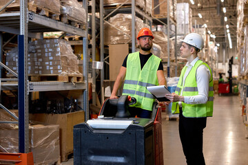 Fototapeta premium Young caucasian men workers doing stocktaking of products on shelves in warehouse together, using clipboard and forklift, having talk discussing, controlling and checking. inventory count concept