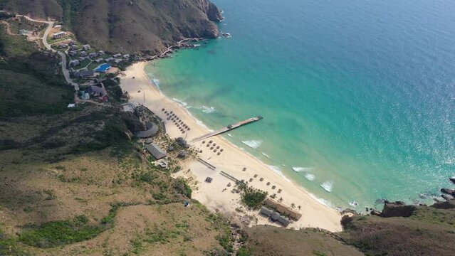 Road, mountain, ocean waves wash sand beach. Aerial daylight above mountain. Tropic nobody nature seascape. Paradise beach of Ky Co, Binh Dinh, Vietnam, Asia at sea bay. Cinematic drone shot