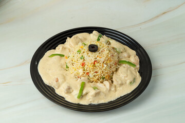 Vegetable fried rice with white chicken gravy served in black platechinese cusine