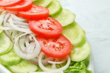 Fresh salad including cucumber,onions and tomatoes on white background.