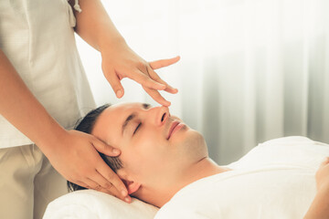 Obraz na płótnie Canvas Caucasian man enjoying relaxing anti-stress head massage and pampering facial beauty skin recreation leisure in dayspa modern light ambient at luxury resort or hotel spa salon. Quiescent