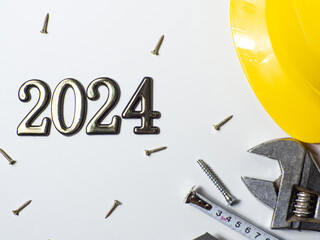 2024 with construction tools, yellow hard hat on white background with copy space. New Year and Christmas construction greeting card. For advertising or web design. Repair home at Christmas. Flat lay.