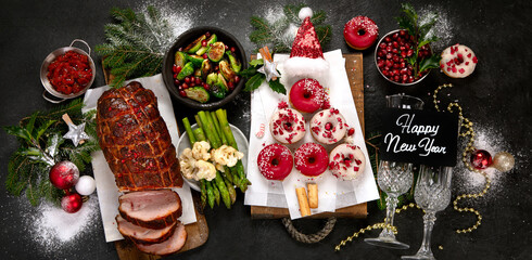 Baked ham with vegetablesand donuts on dark background. Christmas food