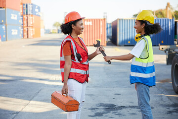 young female African factory workers or engineer giving wrench to colleague after finish work in containers warehouse storage