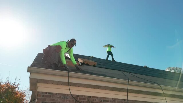 Roofer repair or replace shingle that has been damaged and needing replacement at sunny day. Naperville IL. USA. October 28 2022